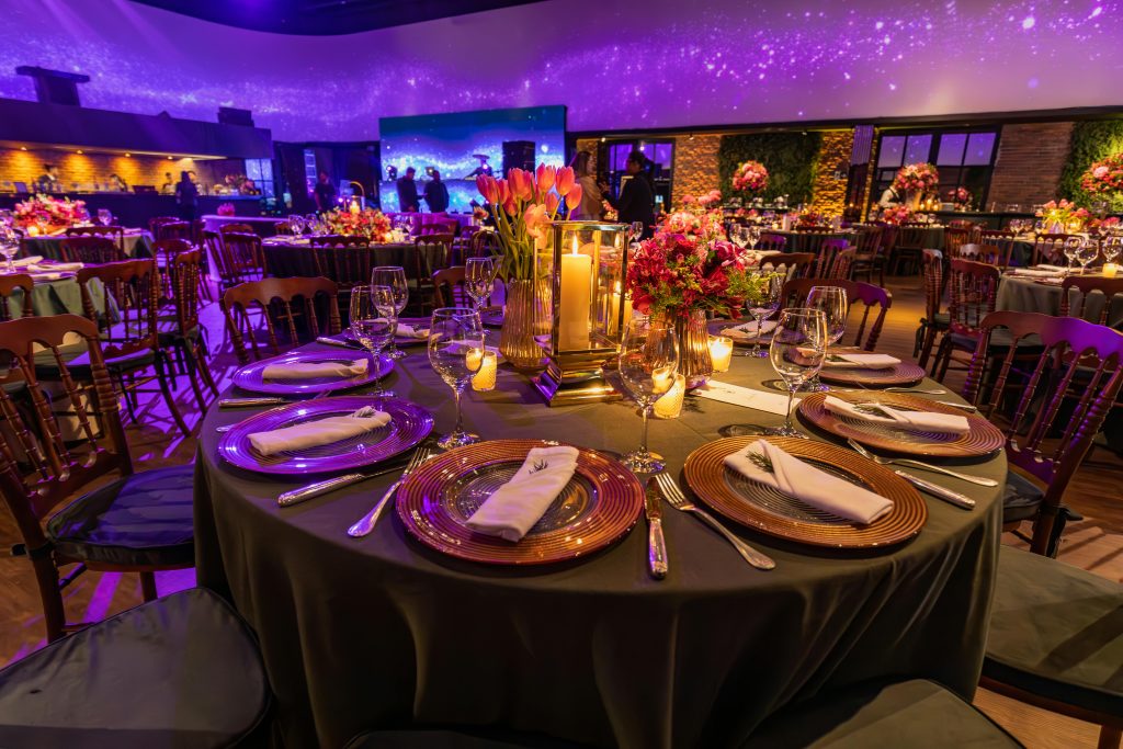 Stunning wedding reception with elegant table settings and floral centerpieces under a glowing ceiling.