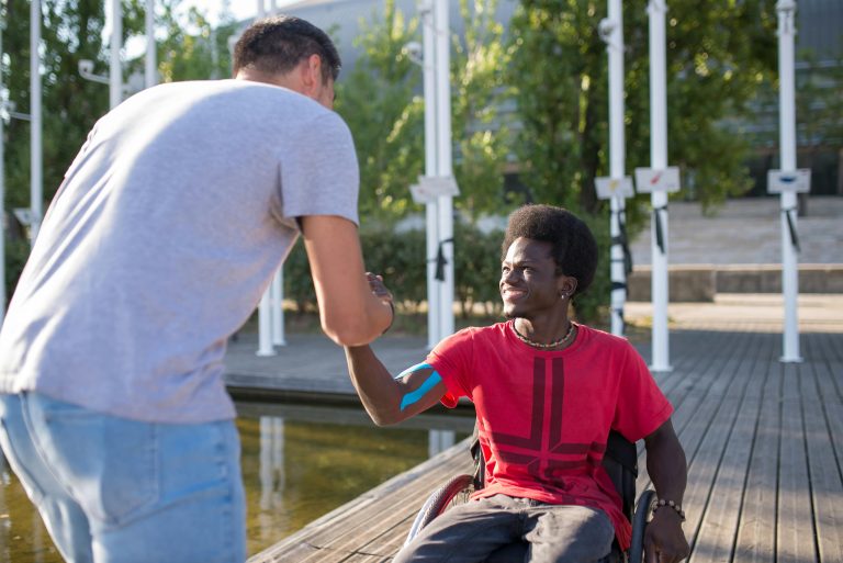 Two men sharing a friendly handshake outdoors in a sunny park.